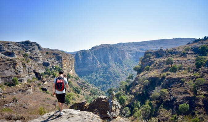 Nomadic Matt wearing a backpack and hiking near a cliff in Madagascar