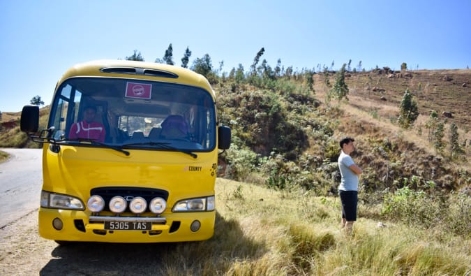 Matt standing next to a yellow bus on side of the road