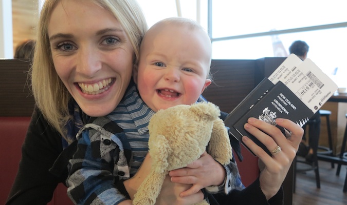 A mom and baby son smiling with travel passports in hand