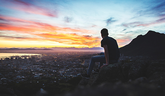a man gazing out over a city landscape at sunset