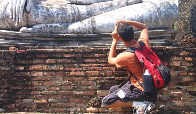 Nomadic Matt kneeling to take a photo while overseas