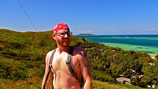 A solo male traveler standing on a hill by the ocean