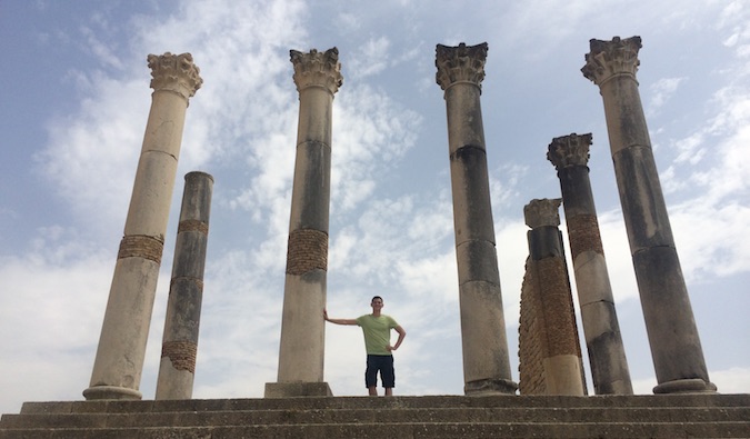 Nomadic Matt posing while enjoying the Roman ruins of Volubilis in Morocco