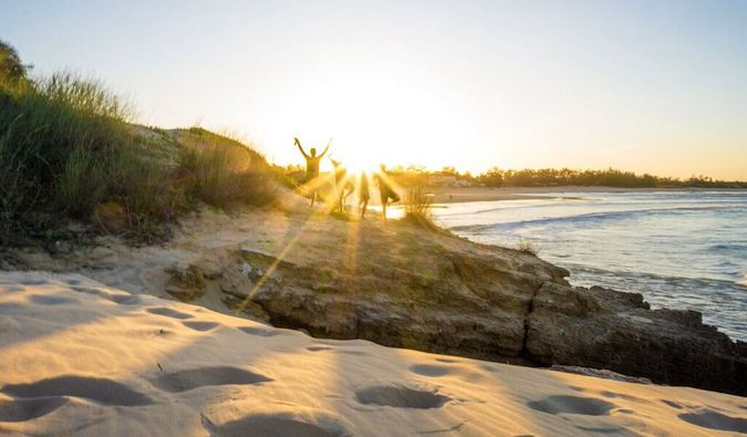 Friends on the beach standing in rays of light