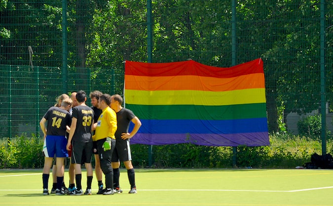 A soccer team standing on a field with a huge pride flag in the background