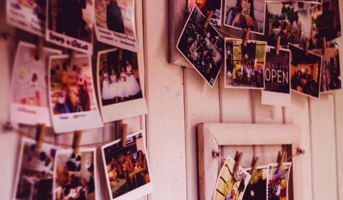 A bunch of old photos hanging on display against a wooden wall