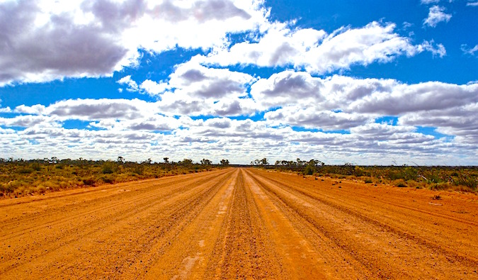 An empty, dusty Australian outback road on a bright and sunny day