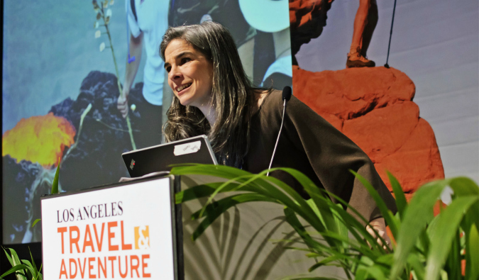 A photo of travel expert Pauline Frommer standing at a podium during a talk