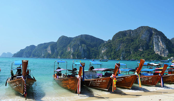 The classic long-tail boats of Thailand all lined up on a beautiful beach in Ko Phi Phi