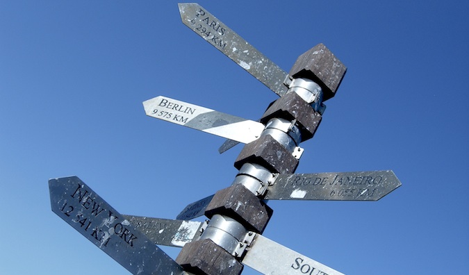 Panneaux indiquant toutes les directions sur un grand panneau avec un ciel bleu en arrière-plan.