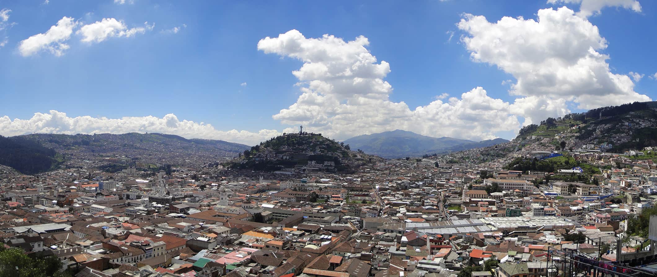 An aerial view of Quito, Ecuador with large hills and mountains surrounding the sprawling city