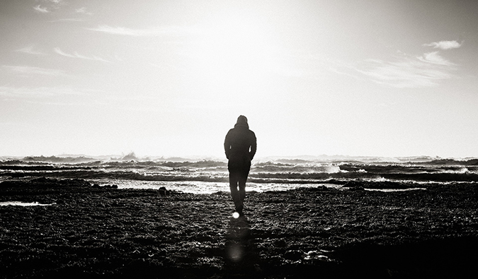 black and white photo of a man walking on a beach