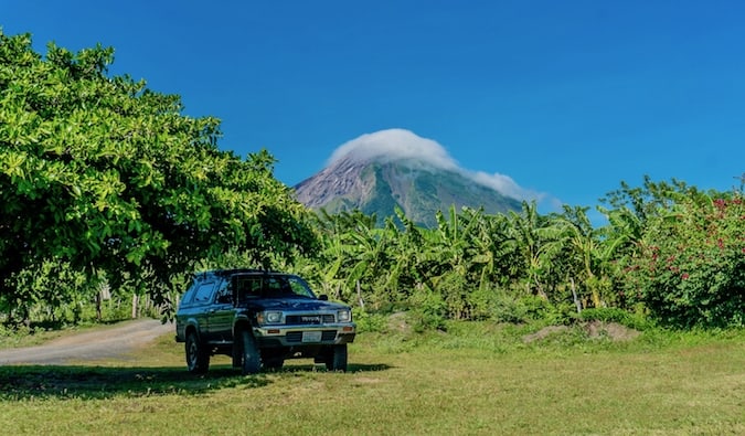 A parked truck in the shade near a large mountain