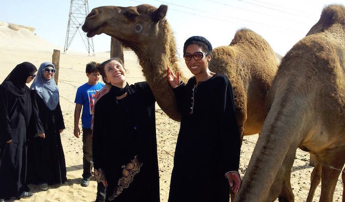 Woman teaching in Saudi Arabia at a camel farm wearing Middle Eastern clothes