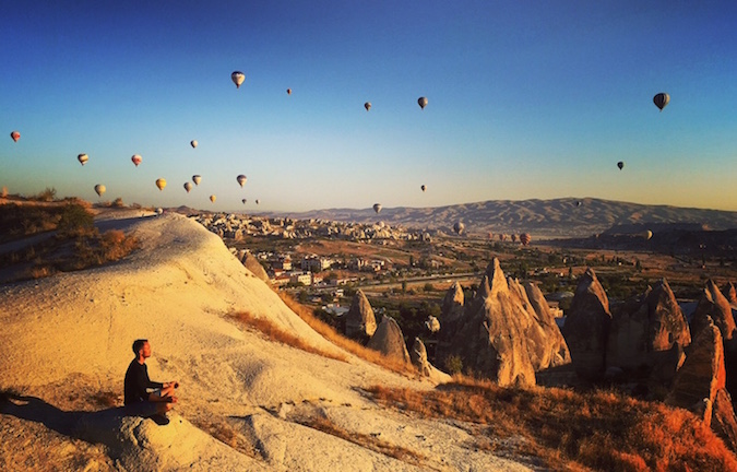 Scott Dinsmore sitting on a rock in Turkey as hot air balloons fill the sky