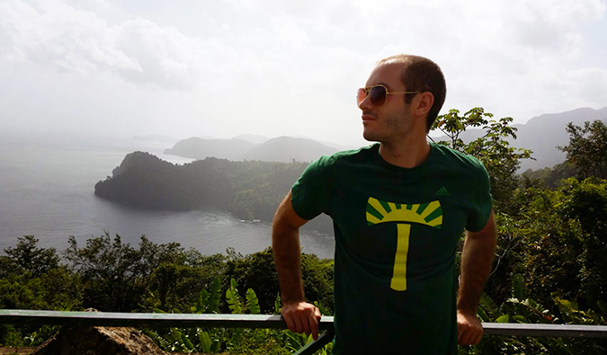 Scott posing in front of a lush, hilly landscape near the ocean