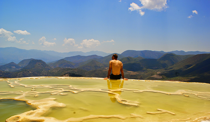 Scott sitting in front of some salt flats surrounded by lush forests and hills