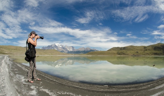 A woman standing in nature taking photos with a professional camera