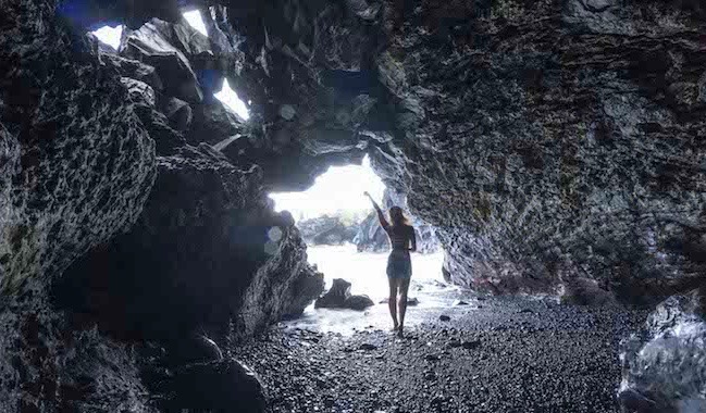 摆在为在洞的一张照片的独奏女性旅客在海洋附近