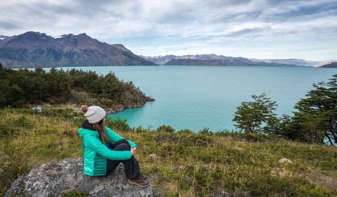 A solo female traveler posing on a dock near the mountains