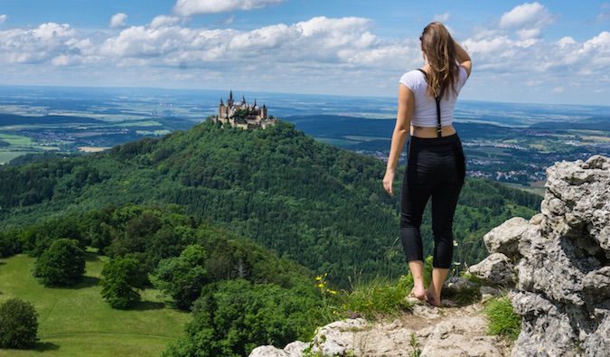 Kristin looking at a beautiful castle in the distance atop a lush green hill in Europe