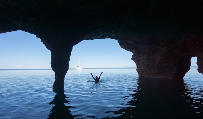 A solo female traveler swimming near ocean caverns