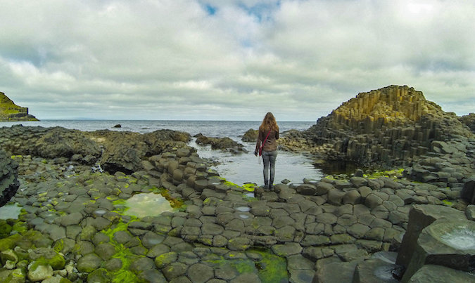 Solo female traveler looking at beautiful rocky Icelandic landscape near the ocean