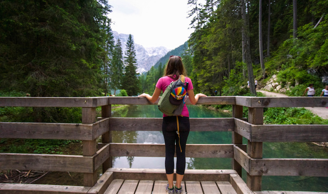 Solo female traveler looking over a picturesque forest landscape near a river