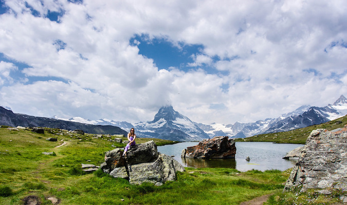 Solo female traveler sitting on a rock in a beautiful landscape overseas