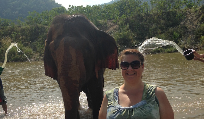 A female traveler bathing an elephant in Chiang Mai, Thailand