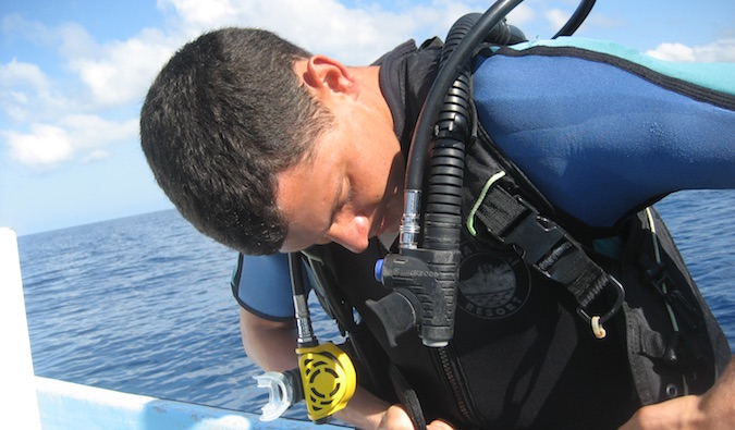 Matt putting on his scuba gear while sitting in a boat