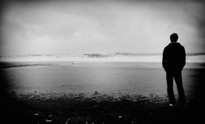 A black and white photo of an uphappy traveler looking out into the distance