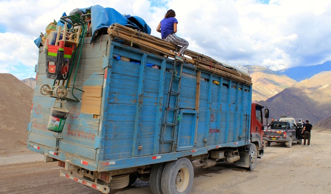 backpacker hitchhiking on top of a truck in Peru