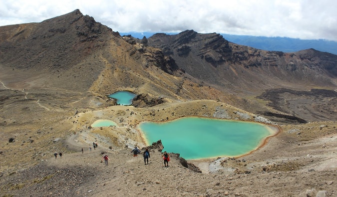 Hikers crossing the martian terrain of the Tongariro Crossing in New Zealand