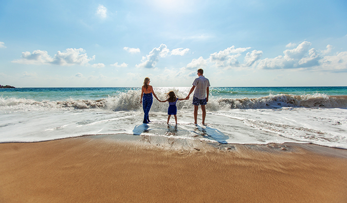 A traveling family at the beach stanind near the water