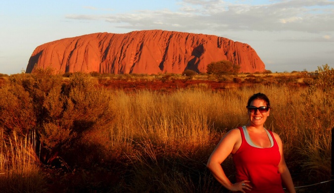 A solo female traveler posing near Uluru in Australia