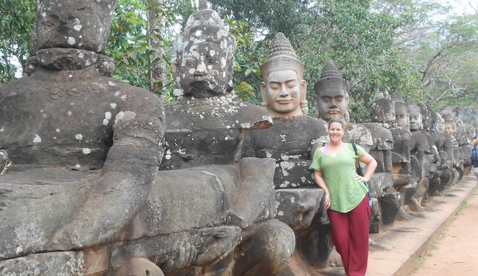 一位独自一人的女性旅行者在宗教雕像旁摆好姿势，环游世界