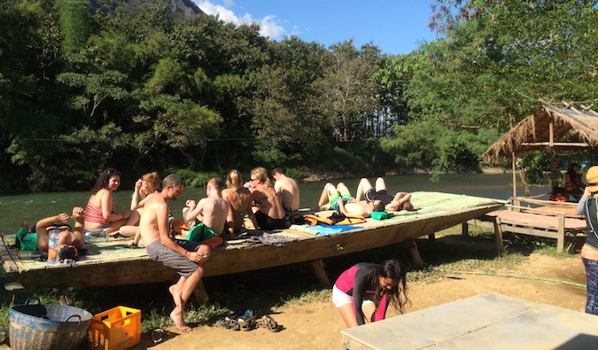 Backpackers hanging out by the water being lazy in Vang Vieng, Laos