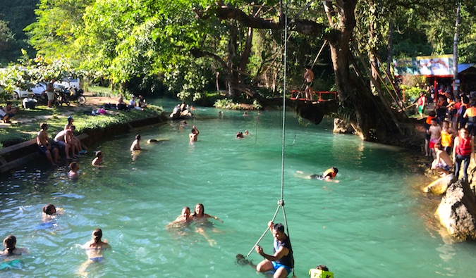 A group of backpackers playing around in Vang Vieng's river while drinking