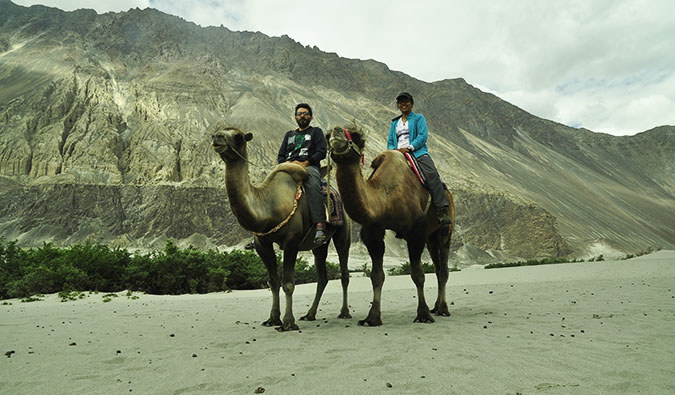 Vikram and Ishwinder from Empty Rusacks sitting on camels posing for a photo