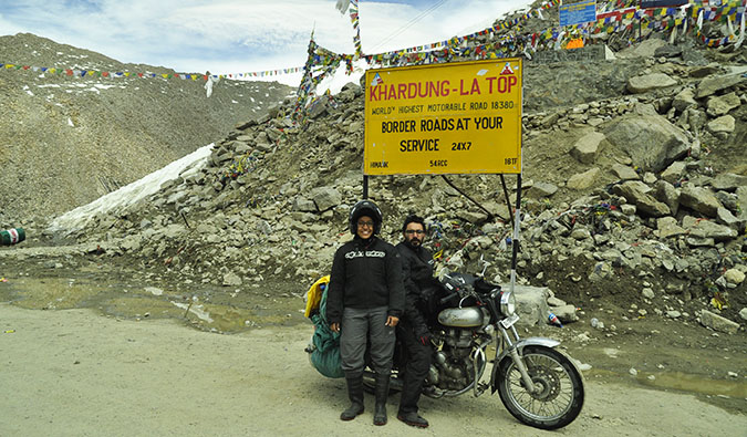 Vikram and Ishwinder from Empty Rusacks posing on their motorcycle near a mountain