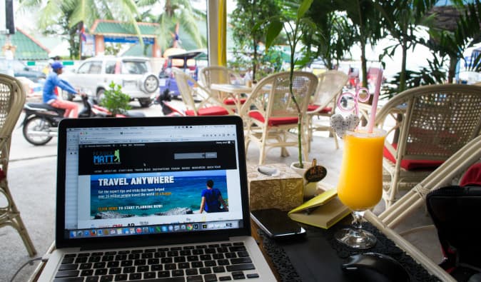 Nomadic Matt travaillant à distance d'un ordinateur portable sur un site Web à l'étranger dans le Cambodge tropical