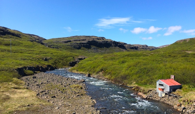 A small hut beside a shallow stream in the Westfjords, Iceland